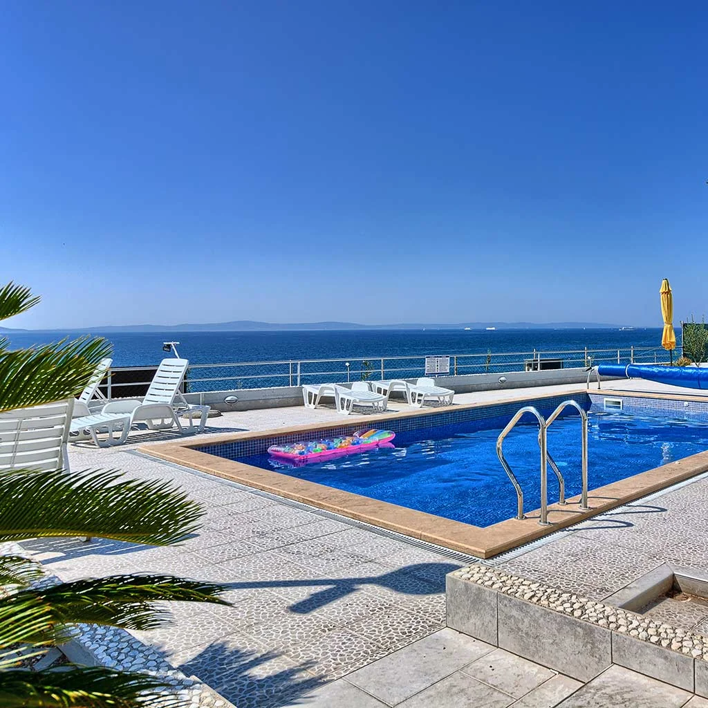 Pool, white sun loungers and sea view